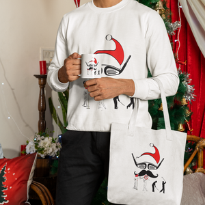 White Man wearing a white Christmas Santa Hat Golf Sweatshirt holding a Christmas Mug and a white Christmas themed tote shopping white bag  